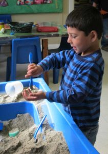 Boy playing with sand at the sensory table